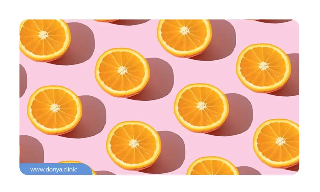 عکس برش های پرتقال روی یک سطح صورتی رنگ